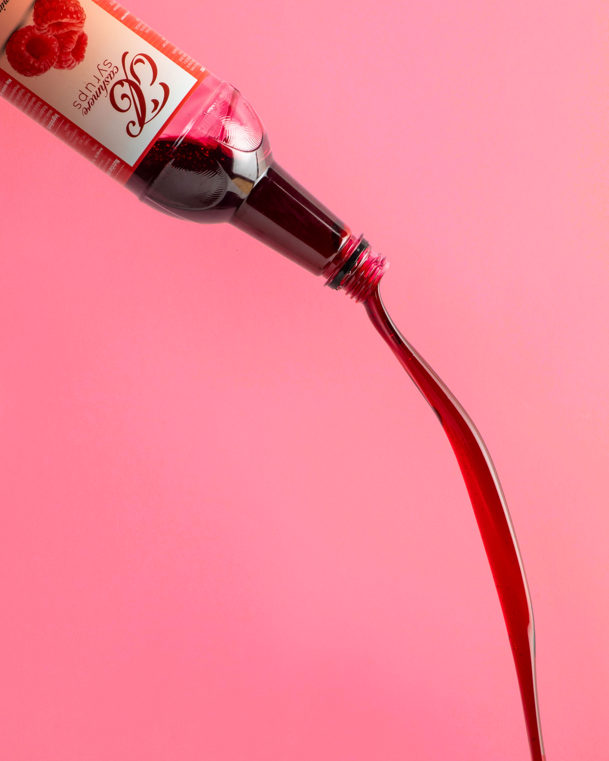 Bottle of raspberry syrup with a visible Cashmere Syrups brand label on a pink background