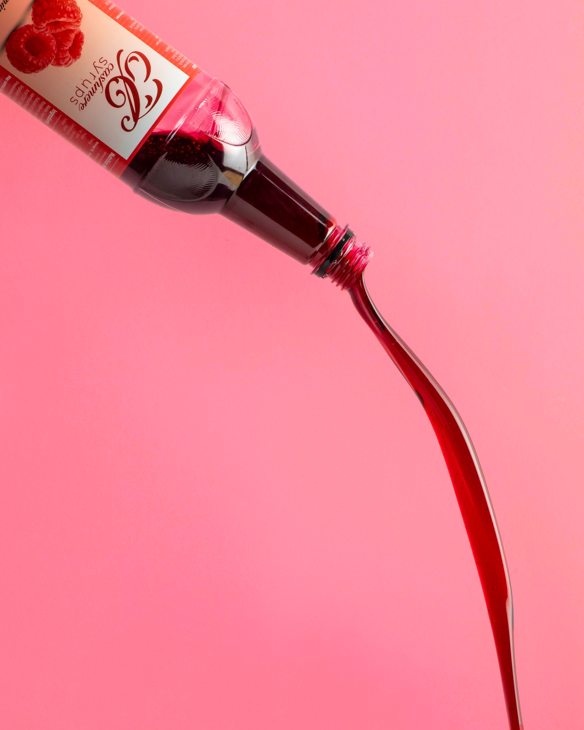 Bottle of raspberry syrup with a visible Cashmere Syrups brand label on a pink background